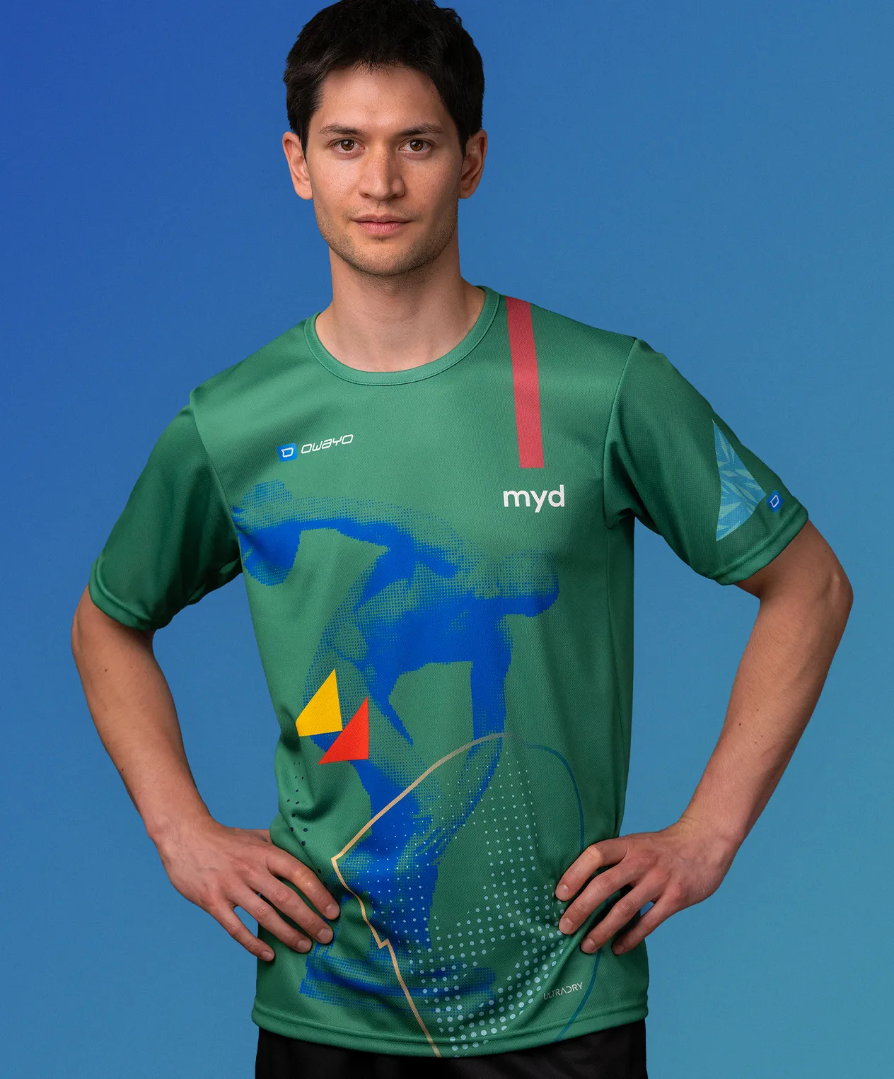 A man wearing a green customized sportswear shirt from owayo featuring a blue, yellow, and red graphic design and the word 'myd' on the chest.